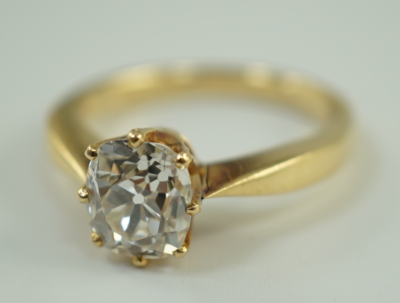 An 18k gold and oval cushion cut solitaire diamond ring